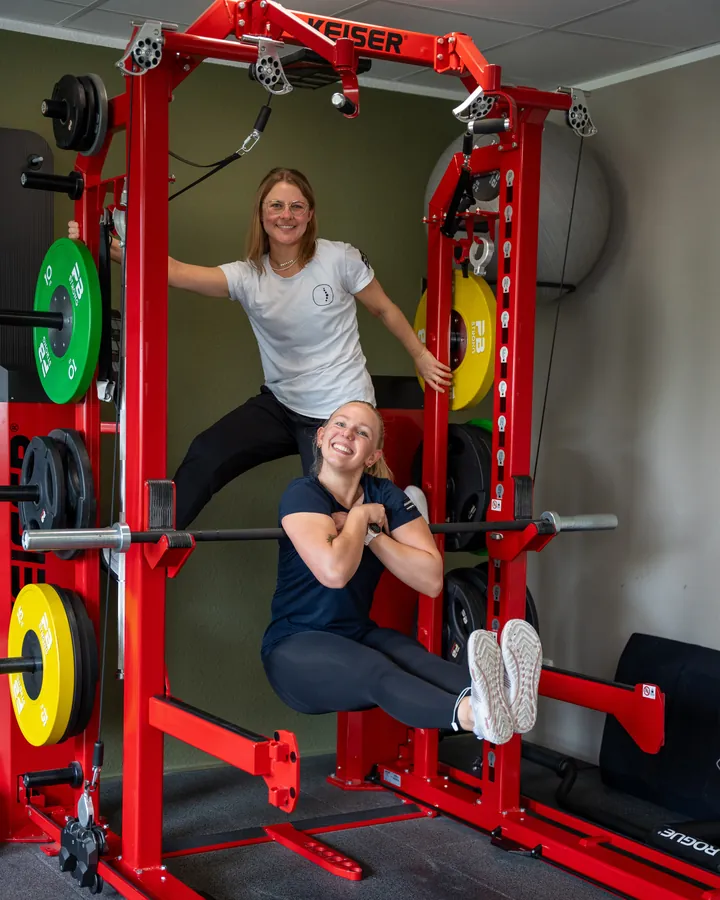 Zwei Kolleginnen haben Spaß am roten KEISER-Rack im Trainingsraum